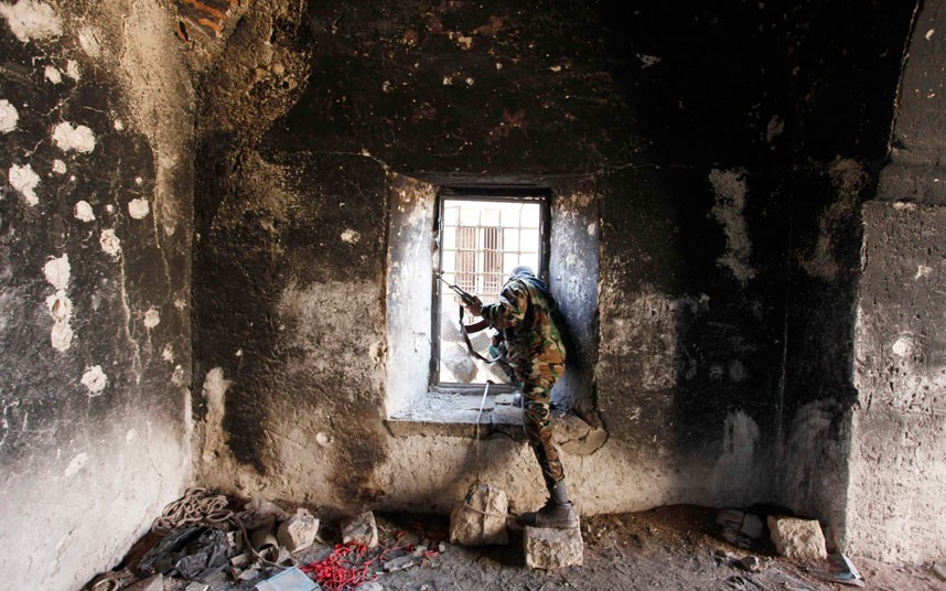 A Free Syrian Army fighter looks through a window of a damaged house in Aleppo. (Reuters/Molhem Barakat)