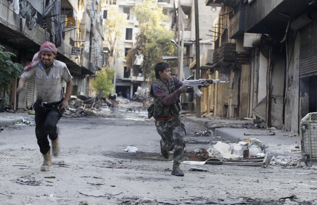 13-year-old Mohammad, a fighter in the Free Syrian Army, aims his weapon as he runs from snipers loyal to the Assad regime in Aleppo. (Reuters/Molhem Barakat)
