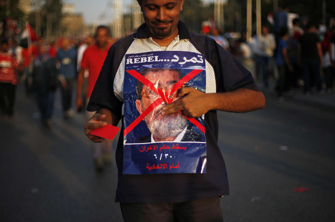 An opposition protestor poses with an anti-Morsi poster in Egypt
