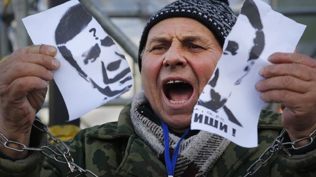 An opposition protestor poses with a ripped image of Yanukovych