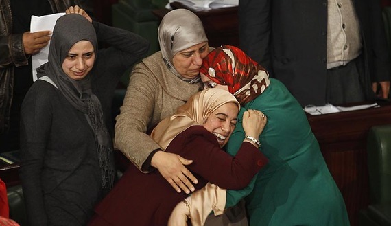 Members of the Tunisian parliament celebrate after approving the country's new constitution in the assembly building in Tunis