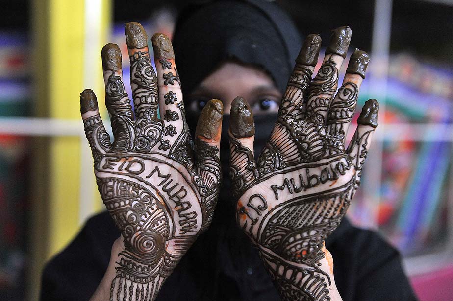 A Muslim woman decorates her hand with Henna in celebration of Eid