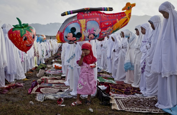 A girl eats ice cream as Indonesian Muslims perform Eid prayers