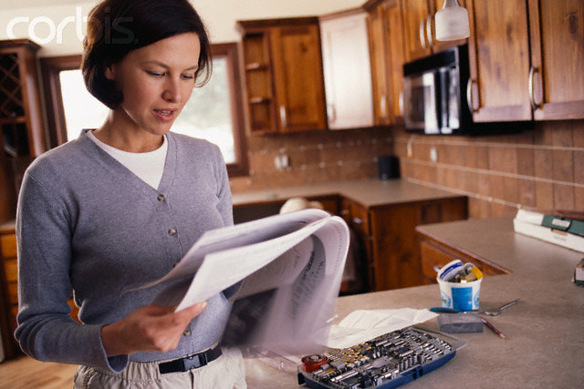 Woman Reading Manual in Kitchen