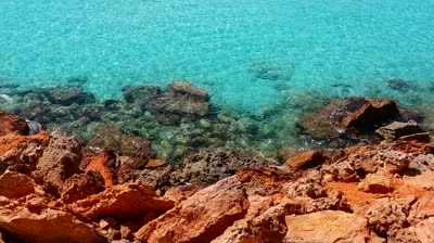 stock-footage-formentera-transparent-turquoise-sea-water-and-red-rocks-shore-in-balearic-islands
