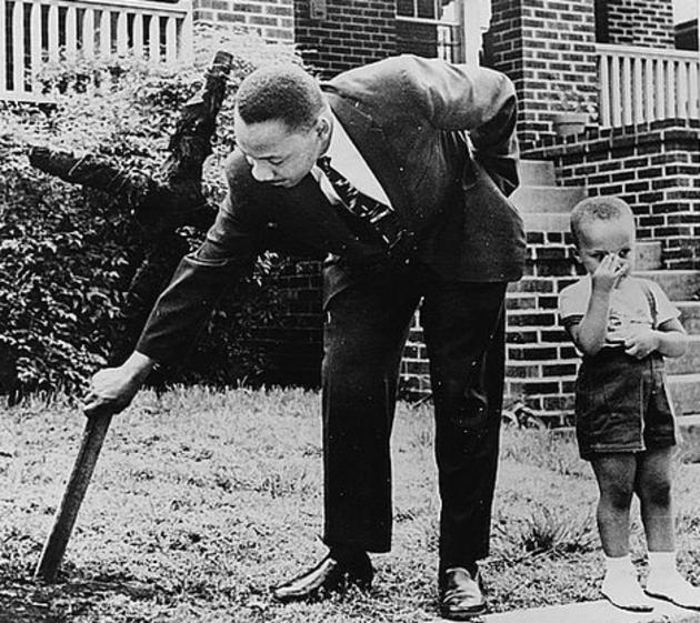 Martin Luther King, Jr., pictured with his son, removing a burned cross from his front yard.