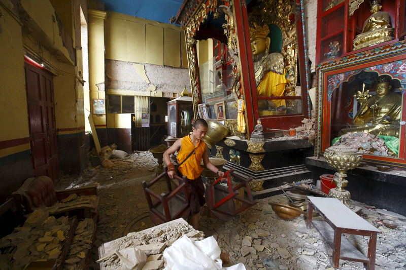 A monk carrying chairs walks out from the damaged monastery at Swoyambhunath Stupa, a UNESCO world heritage site. (Navesh Chitrakar)