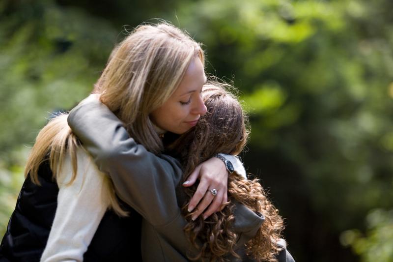 Mother and daughter hugging outdoors