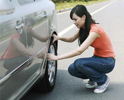174576-425x341-Woman-looking-at-car-tire-TS-new2