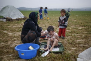 A woman bathes a child at a makeshift camp for migrants and refugees at the Greek-Macedonian border near the village of Idomeni, Greece, April 3, 2016. REUTERS/Marko Djurica
