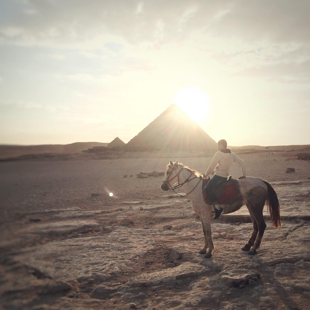 Boy riding a horse at sunset at the Pyramids of Giza